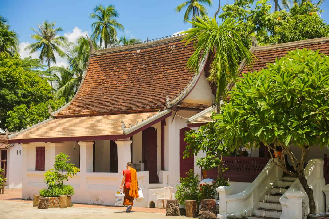 Ancient Thai temple surrounded by tropical plants and tall palm trees.