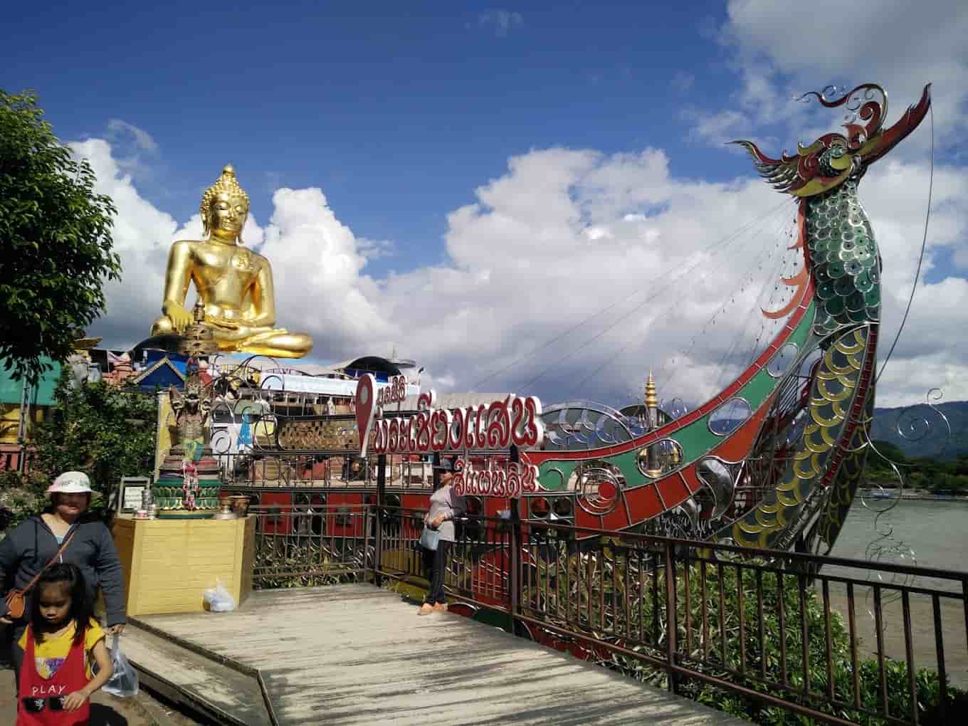 Iconic Golden Triangle statue and dragon sculpture in a scenic riverside setting.