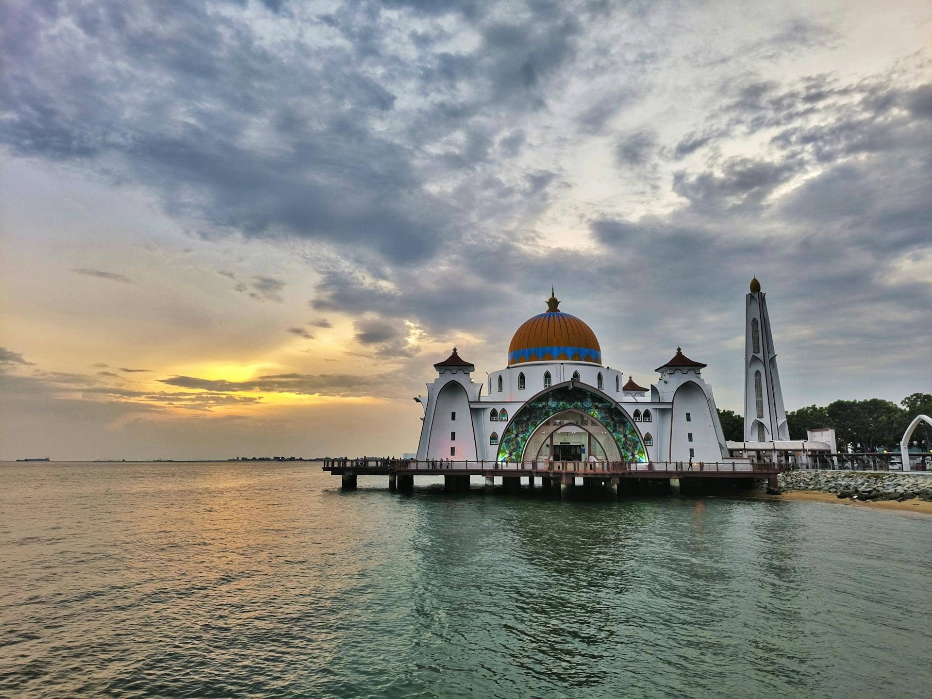 Floating mosque in Melaka, Malaysia, with scenic sunset view and calm waters.