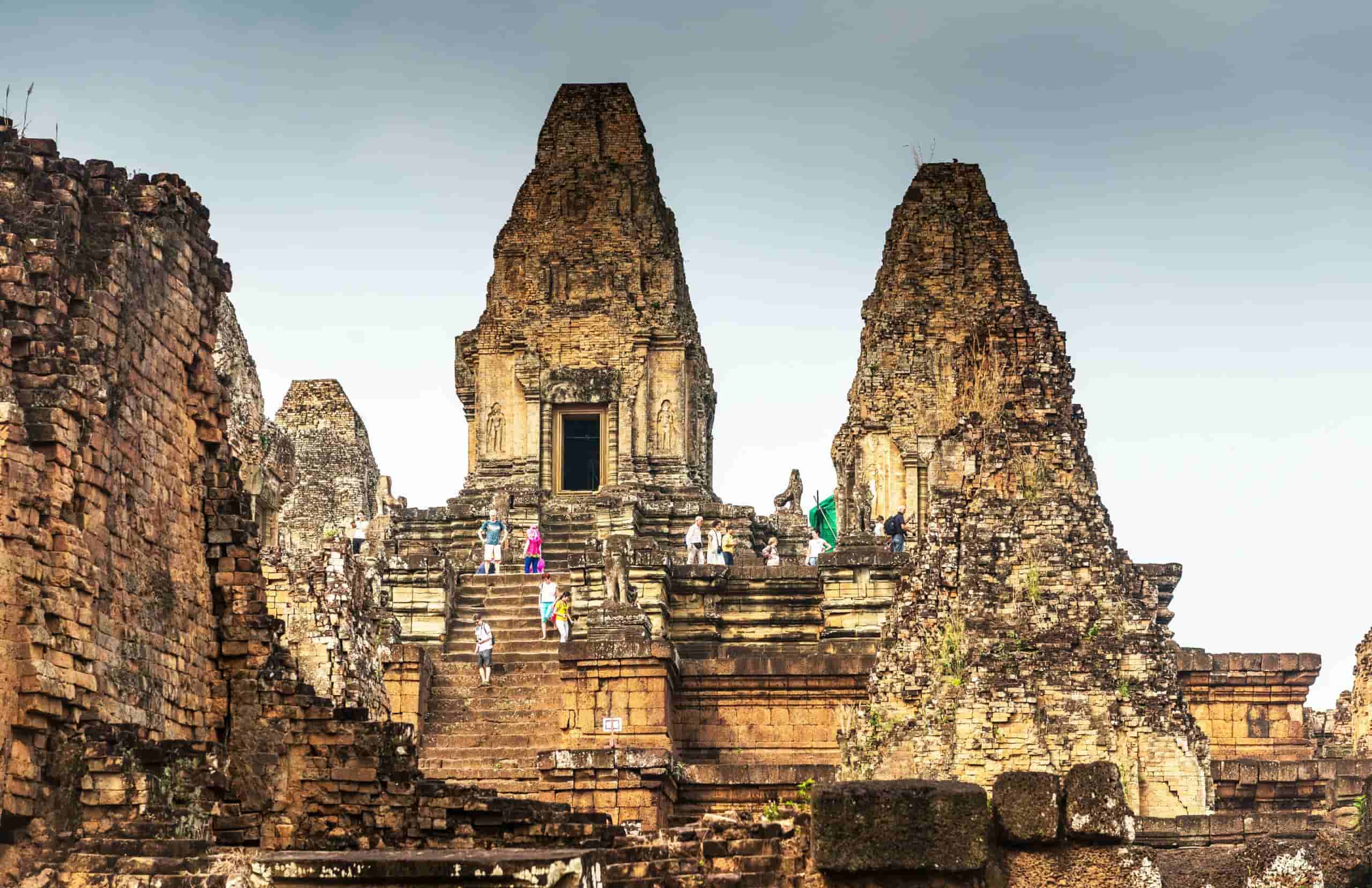 Ancient temple ruins in Cambodia, showcasing historic stone structures and steps with visitors explo.